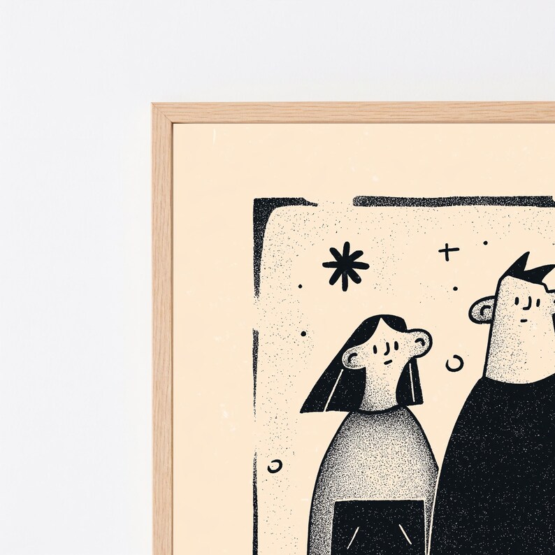 May include: A framed wall art print featuring a black ink illustration of two figures with stippled shading on a light cream background. The artwork is enclosed in a light-coloured wooden frame and includes simple graphic elements like stars.