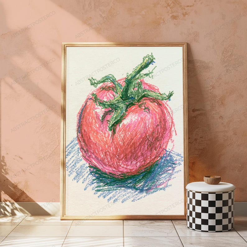 May include: A framed wall art print featuring a crayon-style drawing of a single red tomato with a prominent green stem. The artwork uses textured, layered strokes in shades of red, pink, and green against a light, off-white background.