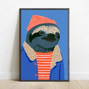 May include: A framed wall art print featuring a stylized illustration of a sloth wearing a coral-colored beanie, a blue jacket with a beige faux-fur collar, and a red and white striped shirt against a solid blue background.