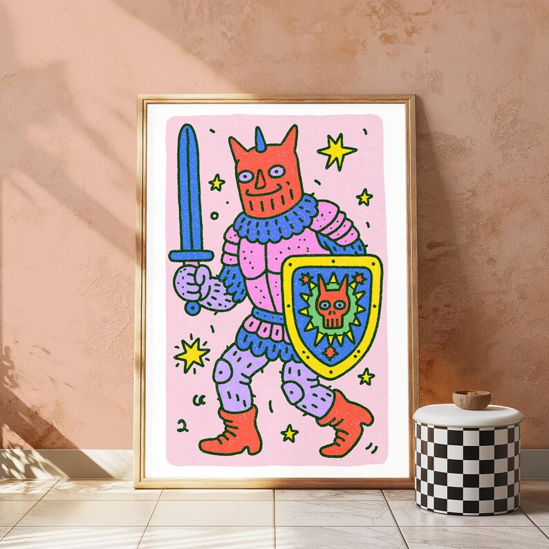 Peut inclure: Une impression d'art encadr&eacute;e repr&eacute;sentant un personnage de dessin anim&eacute; &agrave; t&ecirc;te rouge cornue, portant une armure rose et bleue, tenant une &eacute;p&eacute;e bleue et un bouclier jaune avec un embl&egrave;me de cr&acirc;ne. Le fond est rose clair avec des &eacute;toiles jaunes.