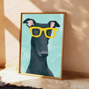 K&ouml;nnte beinhalten: Ein gerahmter Kunstdruck mit einer stilisierten Illustration eines schwarzen Windhundes, der eine leuchtend gelbe Brille tr&auml;gt. Der Hund ist vor einem einfarbigen hellblauen Hintergrund dargestellt und in einem schlichten Holzrahmen gefasst.