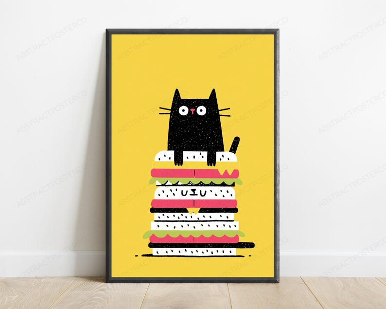 May include: A framed wall art print featuring a black cat with wide eyes sitting atop a tall, multi-layered sandwich. The sandwich consists of white bun layers with black sesame seeds, pink meat slices, and green lettuce, all set against a bright yellow background.