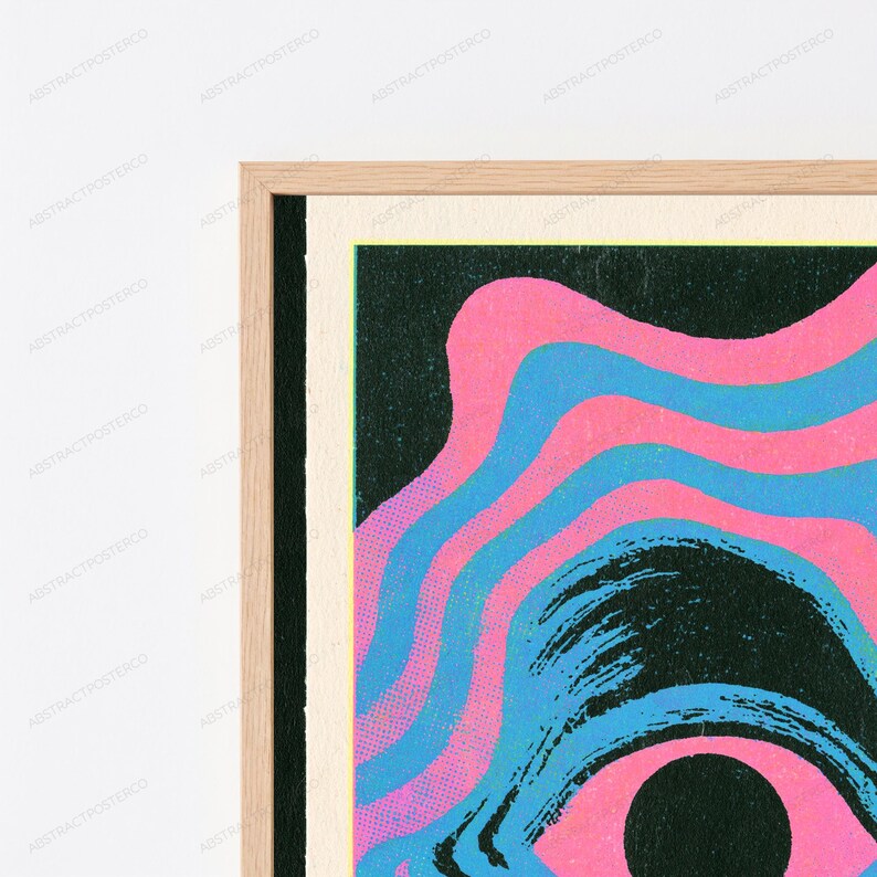May include: A framed wall art print featuring a graphic design with wavy, concentric bands of bright pink and light blue against a dark black background. The artwork is enclosed in a light-colored wooden frame with a visible grain texture.