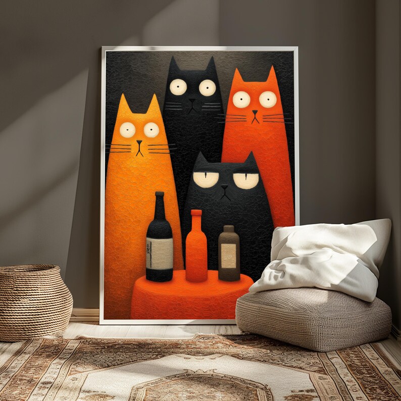 May include: A framed art print featuring four stylized cats in orange and black against a dark background. The cats are positioned in front of a small orange table with three bottles. The artwork is displayed in a room with a woven basket, rug, and a pillow.