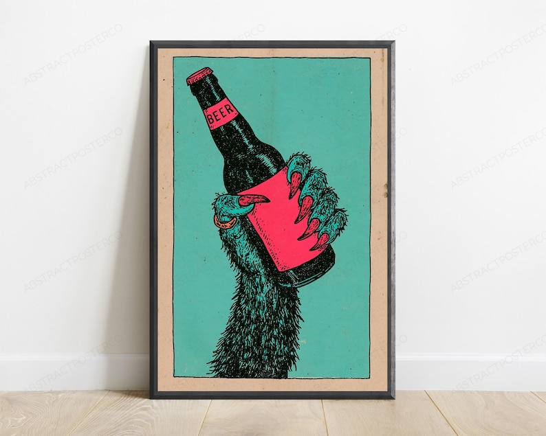 May include: A framed poster featuring a dark, furry creature's hand with sharp claws holding a black beer bottle. The bottle has a bright pink label with the word BEER printed in black. The background is a solid teal colour with a tan border.