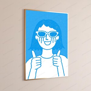 May include: A framed wall art print featuring a stylized illustration of a person with short hair wearing sunglasses. The figure has a wide smile and is giving a thumbs-up with both hands. The design uses a bright blue and white color palette.
