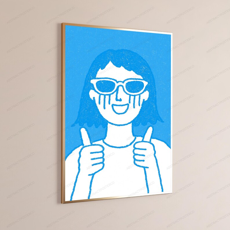 May include: A framed wall art print featuring a stylized illustration of a person with short hair wearing sunglasses. The figure has a wide smile and is giving a thumbs-up with both hands. The design uses a bright blue and white color palette.