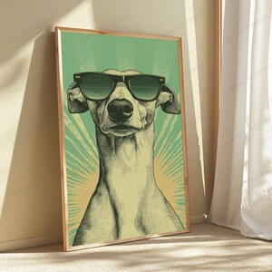 May include: A rectangular framed wall art print featuring a stylized illustration of a greyhound dog wearing black sunglasses. The dog is centered against a light green background with radiating sunburst lines in a lighter shade of yellow and green.