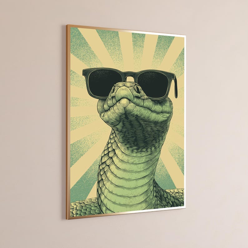 May include: A framed wall art print featuring a detailed illustration of a green snake wearing black sunglasses. The snake is positioned against a background of radiating light yellow and teal sunburst lines, creating a high-contrast graphic design.