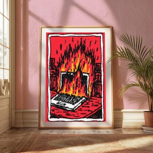 May include: A framed art print featuring a stylized, hand-drawn illustration of a laptop engulfed in bright orange and yellow flames. The artwork uses bold black outlines against a vibrant red background, depicting the computer on a desk surface.