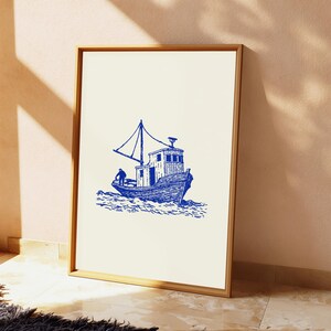 Pu&ograve; includere: Una stampa d'arte incorniciata con un'illustrazione a inchiostro blu di un peschereccio su sfondo color crema. Il disegno raffigura una piccola imbarcazione con un albero e una figura sul ponte, posta su onde stilizzate in una composizione pulita.