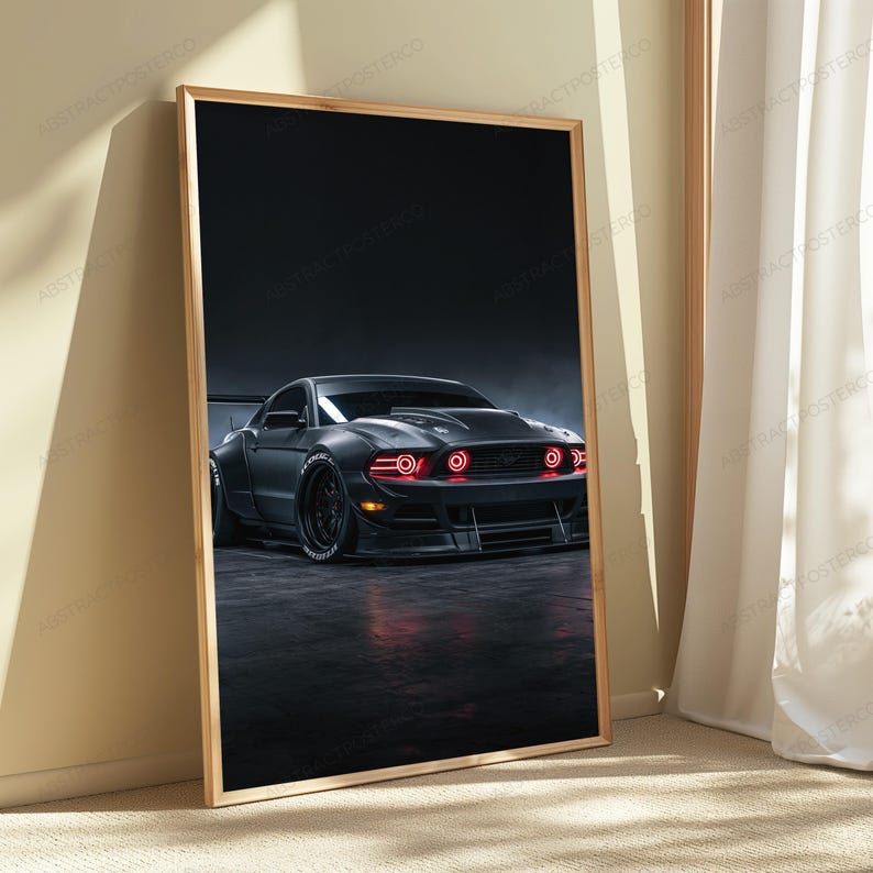 May include: A framed vertical wall art print featuring a matte black sports car with wide fenders and a large rear wing. The vehicle is positioned on a dark surface, showcasing glowing red circular headlights and a low-profile front bumper design.