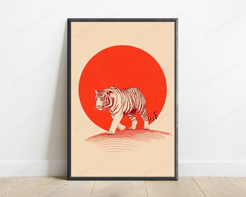 May include: A framed wall art print featuring a tiger illustrated in dark red lines walking across a curved horizon line. Behind the tiger is a large, solid red circle set against a light beige background. The frame is thin and black.
