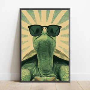 K&ouml;nnte beinhalten: Ein gerahmter Kunstdruck, der eine gr&uuml;ne Schildkr&ouml;te mit schwarzer Sonnenbrille zeigt. Die Schildkr&ouml;te ist vor einem Hintergrund aus strahlenden, hellbeigen und gr&uuml;nen gepunkteten Sonnenstrahlen zentriert. Die Illustration nutzt einen Grafikstil.