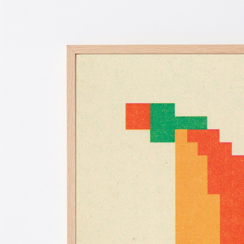 K&ouml;nnte beinhalten: Ein gerahmter Wandkunstdruck mit einem verpixelten Grafikdesign auf hellcremefarbenem Hintergrund. Das Kunstwerk zeigt eine Reihe gestapelter geometrischer Bl&ouml;cke in leuchtenden Orange-, Rot- und Gr&uuml;nt&ouml;nen, eingefasst in einen hellen Holzrahmen.
