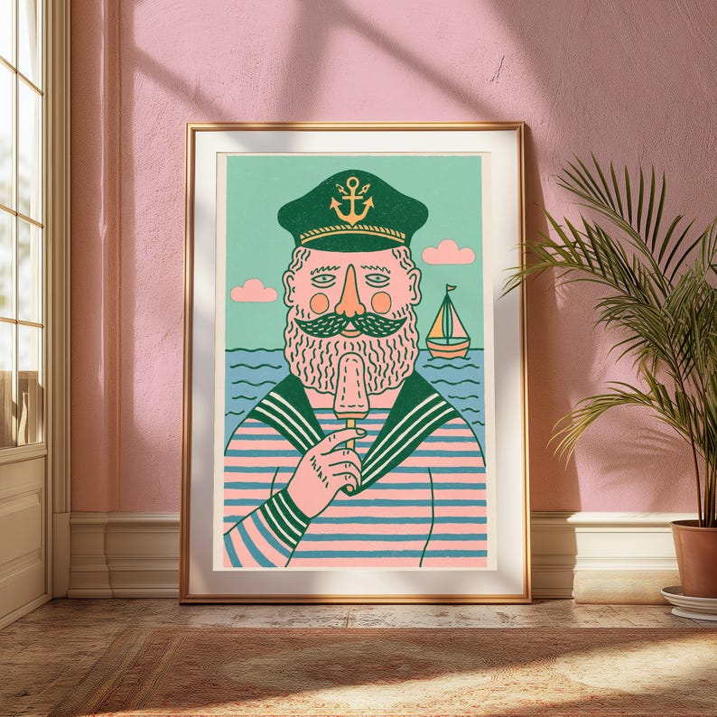 K&ouml;nnte beinhalten: Ein gerahmter Kunstdruck zeigt einen b&auml;rtigen Seemann mit einer gr&uuml;nen M&uuml;tze mit goldenem Ankeremblem und einem rosa-blau gestreiften Hemd. Der Seemann isst ein Eis vor einem Hintergrund aus blauen Meereswellen, einem kleinen Segelboot und rosa Wolken.