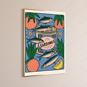 Pode incluir: Uma impress&atilde;o art&iacute;stica retangular emoldurada apresentando uma lata central com o r&oacute;tulo SARDINES cercada por ilustra&ccedil;&otilde;es estilizadas de peixes, frutas rosas texturizadas com folhas verdes, pequenas estrelas-do-mar e um gomo de lim&atilde;o amarelo sobre um fundo azul com pontos amarelos.