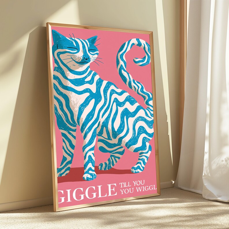 May include: A framed vertical art print featuring a stylised cat with blue and white wavy stripes against a solid pink background. The cat has a curved tail and a smiling expression. The text GIGGLE TILL YOU WIGGLE is printed in white at the bottom.