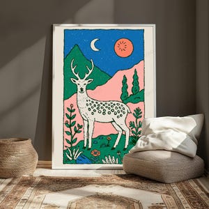 May include: A rectangular wall art print featuring a white spotted deer standing in a landscape with green mountains, pink hills, and a blue starry sky with a crescent moon and a red sun. The foreground includes stylized green plants and flowers.