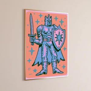 May include: A framed wall art print featuring a stylized illustration of a knight in armor, holding a sword in the right hand and a shield with a star emblem in the left. The figure is rendered in blue and pink tones against a coral background.