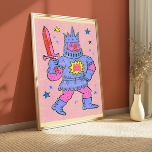 May include: A framed wall art print featuring a stylized illustration of a knight in blue armor and a crown, holding a red and orange sword. The knight has pink skin and a yellow sun emblem on the chest, set against a textured light pink background with scattered blue, green, and yellow stars.