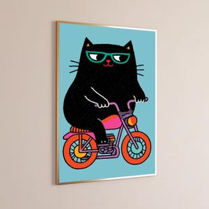 K&ouml;nnte beinhalten: Ein gerahmter Kunstdruck, der eine schwarze Katze mit t&uuml;rkisfarbener Brille auf einem violetten Motorrad mit leuchtend orangefarbenen R&auml;dern vor hellblauem Hintergrund zeigt. Die Illustration verwendet kr&auml;ftige Linien und Farben.