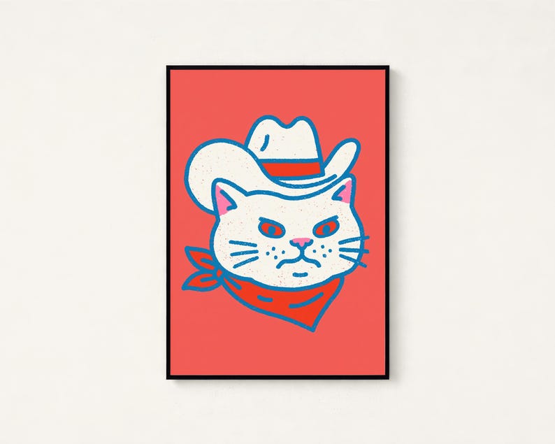 May include: A framed wall art print featuring a stylized illustration of a white cat wearing a white cowboy hat with a red band and a red bandana around its neck, set against a solid coral-red background with bold blue outlines.