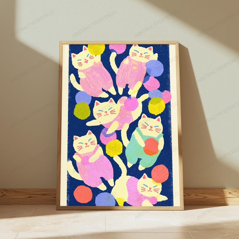 May include: A framed vertical art print featuring a dark blue background with multiple cream-colored cats wearing pink or light green overalls. The cats are surrounded by scattered colorful yarn balls in shades of yellow, pink, blue, and orange.