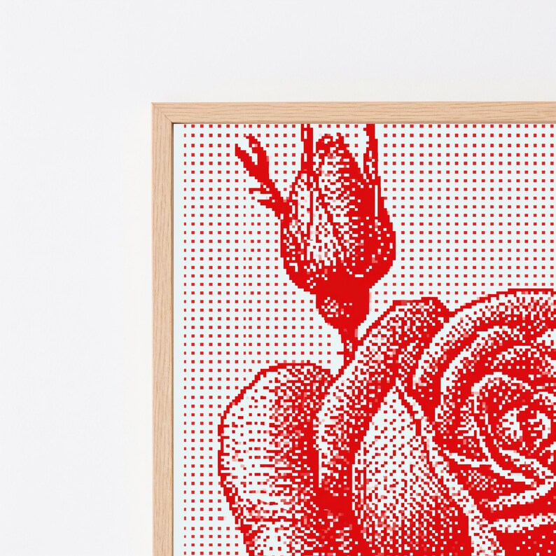 Pode incluir: Uma pe&ccedil;a de arte de parede emoldurada com um design de rosa vermelha pixelizada sobre um fundo branco. A obra exibe um bot&atilde;o de rosa detalhado e uma rosa parcialmente aberta criados com uma grade de pontos vermelhos, numa moldura de madeira clara.