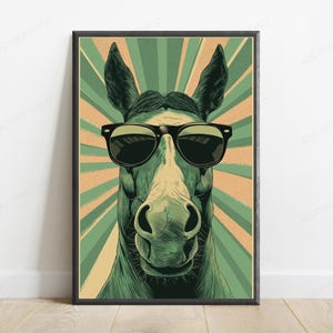 May include: A framed wall art print featuring a stylized illustration of a horse wearing black sunglasses. The horse is centered against a background of alternating light green and tan sunburst rays, creating a graphic, high-contrast visual.
