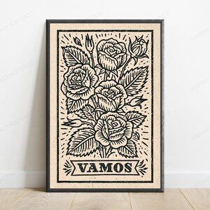 Könnte beinhalten: Ein rechteckiger gerahmter Kunstdruck mit einer schwarzen Tuscheillustration eines Rosenstraußes auf hellbeigem Hintergrund. Das Motiv zeigt drei blühende Rosen, zwei Rosenknospen und Blätter, mit dem Wort VAMOS in einem Banner darunter.