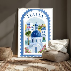 K&ouml;nnte beinhalten: Ein vertikaler, rechteckiger Wandkunstdruck in Form einer Briefmarke mit blauem, gewelltem Rand. Die Illustration zeigt eine Kirche mit blauer Kuppel, wei&szlig;e Geb&auml;ude, eine Palme und rosa Blumen, wobei das Wort ITALIA oben aufgedruckt ist.