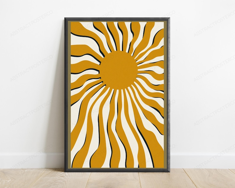May include: A framed wall art print featuring a central solid mustard yellow circle with radiating wavy lines in alternating mustard yellow, cream, and thin black stripes, creating a sunburst pattern within a dark rectangular frame.