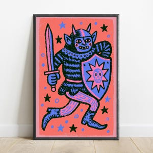 May include: A framed art print featuring a dark blue horned creature in armor, holding a sword and a shield with a pink skull emblem. The background is a vibrant coral color decorated with scattered black and blue stars and small circles.