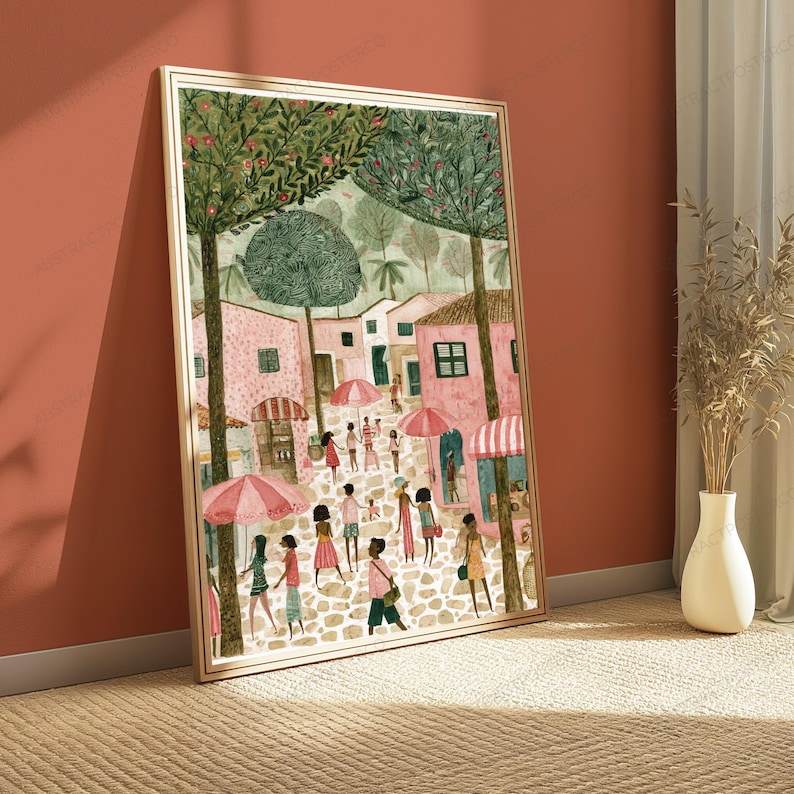 May include: A framed wall art print depicting a bustling town square with pink buildings, cobblestone paths, and people walking under pink and white striped umbrellas. Tall green trees with textured foliage frame the scene in this illustration.