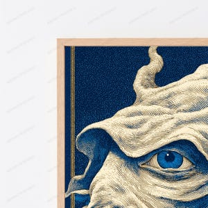 May include: A framed wall art print featuring a detailed illustration of a single blue eye surrounded by cream-colored, flowing fabric-like textures. The background is a deep navy blue with a stippled effect, framed by a light wood border.