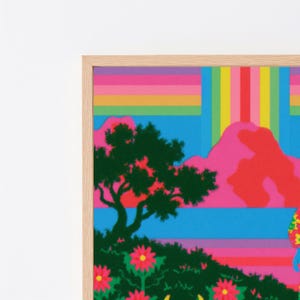 May include: A framed art print featuring a vibrant landscape with a dark green tree and flowers in the foreground, set against bright pink mountains and a sky composed of horizontal and vertical rainbow-colored stripes in a light wood frame.