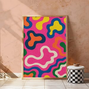May include: A rectangular framed wall art piece featuring a vibrant, textured pattern of irregular, amoeba-like shapes in bright pink, yellow, orange, green, and cream, all outlined with thick, dark blue borders on a solid pink background.