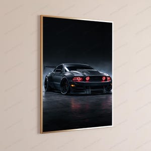 May include: A framed vertical wall art print featuring a matte black sports car with a wide body kit and a rear spoiler. The vehicle is positioned in a dark, moody setting with glowing red circular headlights and amber side marker lights.