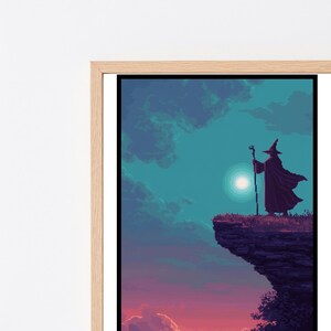 May include: A framed pixel art print depicting a dark silhouette of a robed figure wearing a pointed hat and holding a staff, standing on a cliff edge against a teal sky with a bright circular moon and a purple and orange sunset horizon.