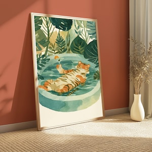 Peut inclure: Une impression d'art encadr&eacute;e repr&eacute;sentant une illustration &agrave; l'aquarelle d'un tigre ray&eacute; orange et noir se relaxant dans une piscine turquoise circulaire. Le tigre tient un verre &agrave; cocktail avec une tranche d'orange. Des feuilles tropicales vertes entourent la piscine.