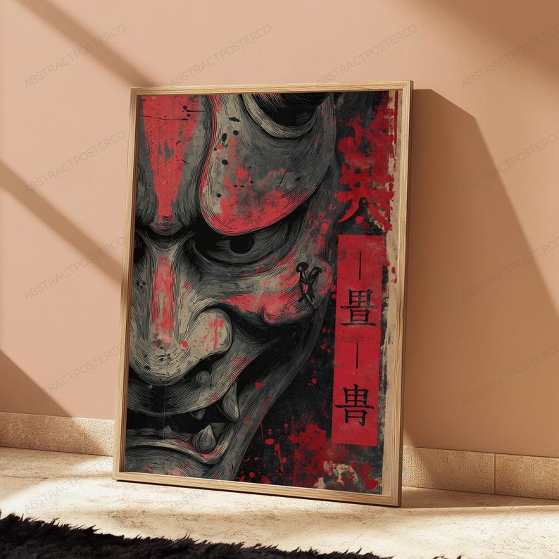K&ouml;nnte beinhalten: Ein rechteckiger Wandkunstdruck in einem hellen Holzrahmen mit einer Nahaufnahme eines grauen und schwarzen Hannya-Maskenmotivs mit roten Farbspritzern. Ein vertikales rotes Rechteck auf der rechten Seite enth&auml;lt schwarze japanische Kanji-Schriftzeichen.