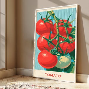 May include: A framed vertical art print featuring a cluster of bright red tomatoes on a green vine against a light blue background with thin vertical white stripes. The word TOMATO is printed in red capital letters at the bottom of the print.