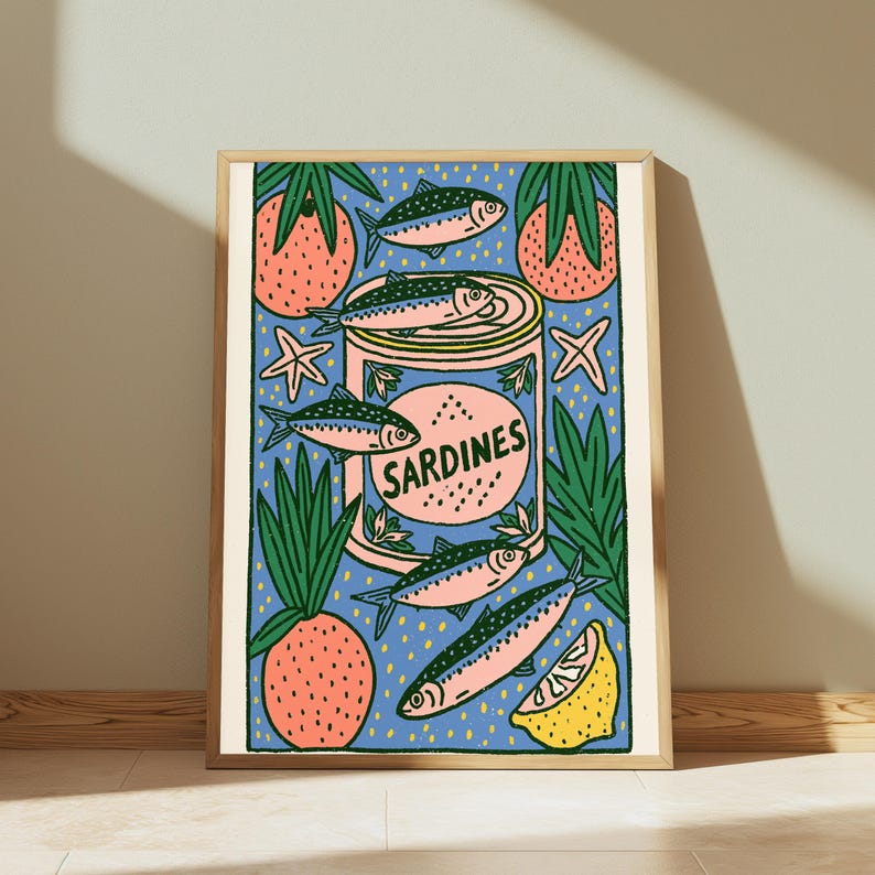 Pode incluir: Uma impress&atilde;o art&iacute;stica emoldurada apresentando uma lata central com o r&oacute;tulo SARDINES rodeada por ilustra&ccedil;&otilde;es de peixes, abacaxis cor-de-rosa com folhas verdes, estrelas-do-mar e uma fatia de lim&atilde;o amarelo num fundo azul com pontos amarelos.