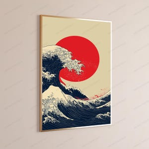 May include: A vertical rectangular wall art print in a thin gold frame featuring a stylized dark blue ocean wave with white foam crests set against a solid beige background with a large, bold, solid red circle positioned behind the wave.