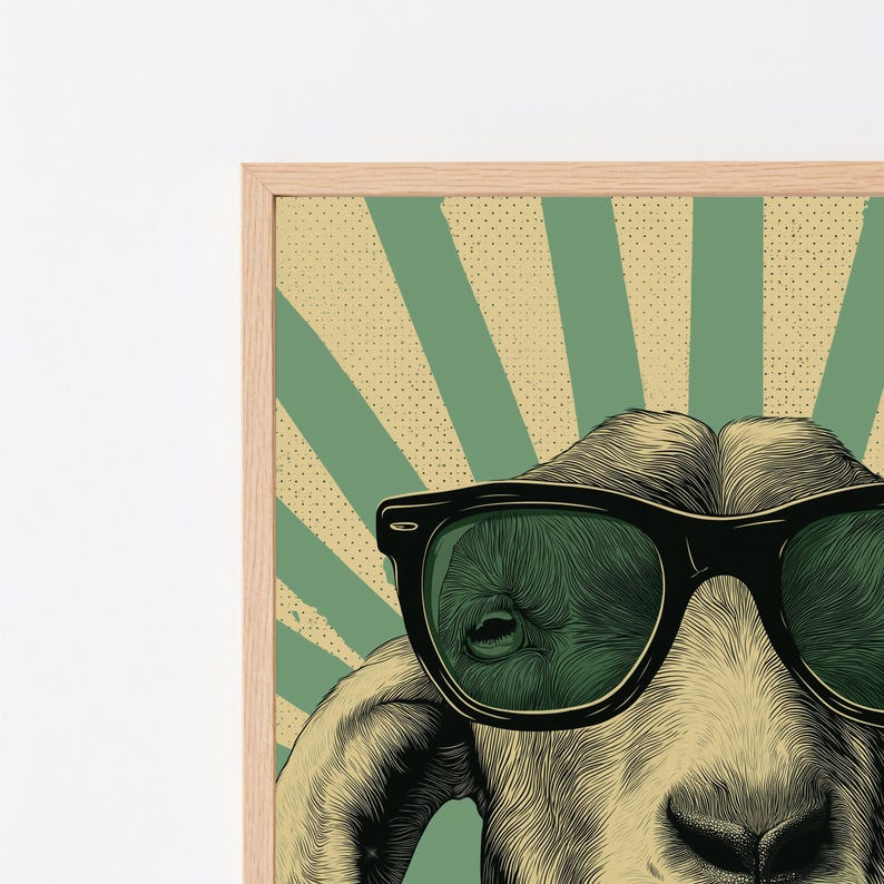 May include: A framed art print featuring a detailed illustration of a goat wearing black-rimmed sunglasses. The background consists of alternating light green and beige sunburst rays with a subtle dotted texture, all encased in a light wood frame.