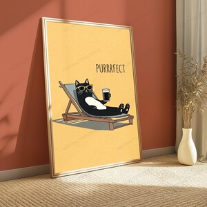 May include: A framed wall art print featuring a yellow background with a black and white cat wearing yellow sunglasses, lounging on a wooden deck chair while holding a dark beverage. The text PURRRFECT is printed in black above the cat.