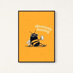 May include: A rectangular wall art print featuring a yellow background with a black and yellow striped bee wearing white sunglasses. The bee is sitting and holding a silver can. The text absolutely buzzing is printed in white above the bee.