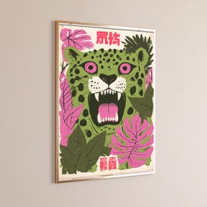 Peut inclure: Une impression d'art encadr&eacute;e repr&eacute;sentant un l&eacute;opard vert stylis&eacute; aux yeux rose vif, la gueule ouverte montrant des dents ac&eacute;r&eacute;es. Le l&eacute;opard est entour&eacute; de feuilles tropicales roses et vert fonc&eacute;, avec des caract&egrave;res chinois roses en haut et en bas.