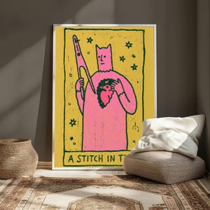 Puede incluir: Una impresi&oacute;n de arte mural rectangular enmarcada con fondo amarillo y borde verde oscuro. Una figura rosa sostiene unas tijeras y una forma de coraz&oacute;n verde oscuro. Peque&ntilde;as estrellas rodean la figura. El texto A STITCH IN T es visible.